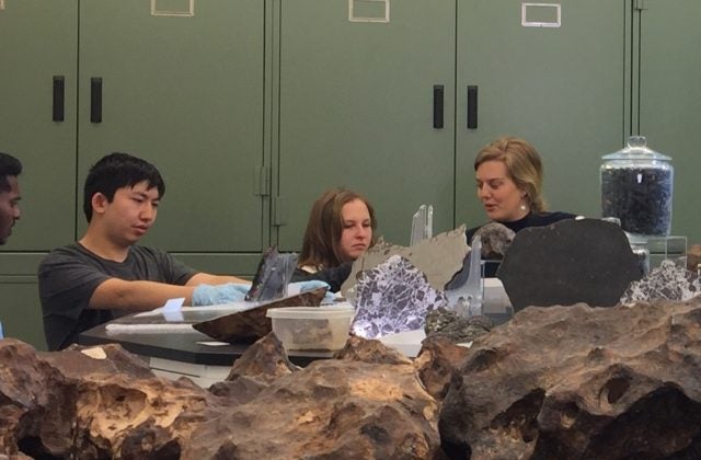 This image shows four university students who are participating in Psyche capstones discussing their projects inside the meteorite vault at Arizona State University's Center for Meteorite Studies.