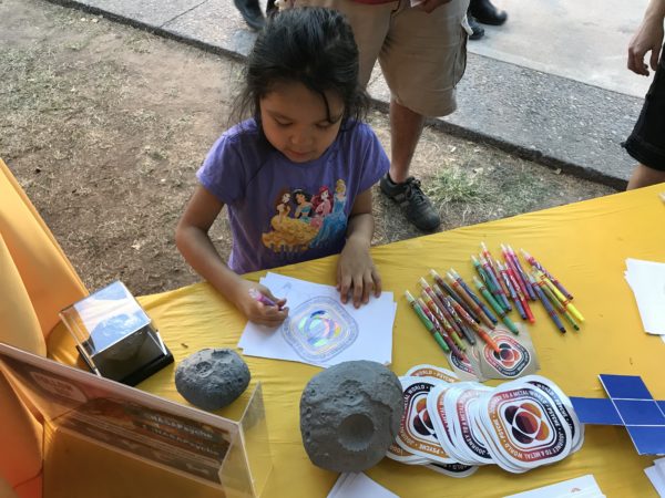 This image shows a young child intently coloring in the Psyche badge.