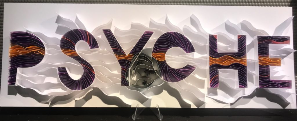 This image shows the word "Psyche" spelled out by many strips of paper that have been adhered on-edge to a background to create a 3D paper piece.