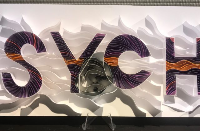 This image shows the word "Psyche" spelled out by many strips of paper that have been adhered on-edge to a background to create a 3D paper piece.