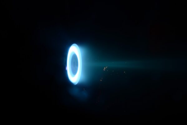 This image shows the Hall thruster, a donut-shaped ring glowing blue on a black background.