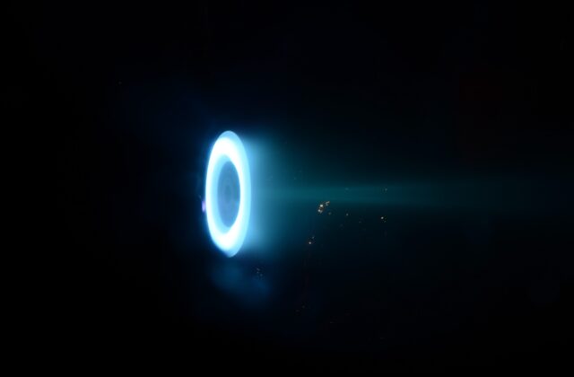 This image shows the Hall thruster, a donut-shaped ring glowing blue on a black background.