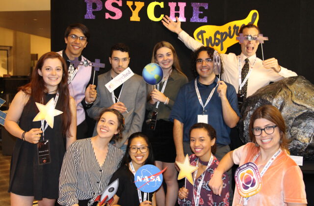 This picture shows 10 psyche inspired interns in the psyche photo booth holding psyche props.