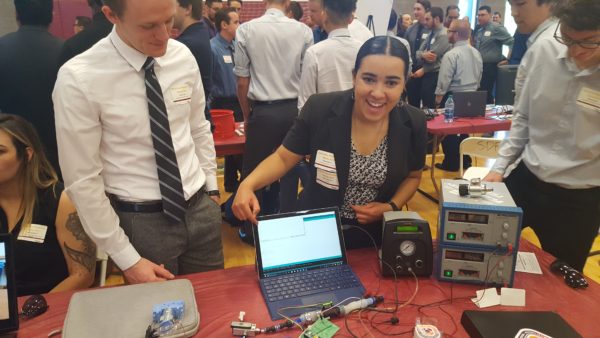 Undergraduate students displaying their protoype controlled by a laptop.