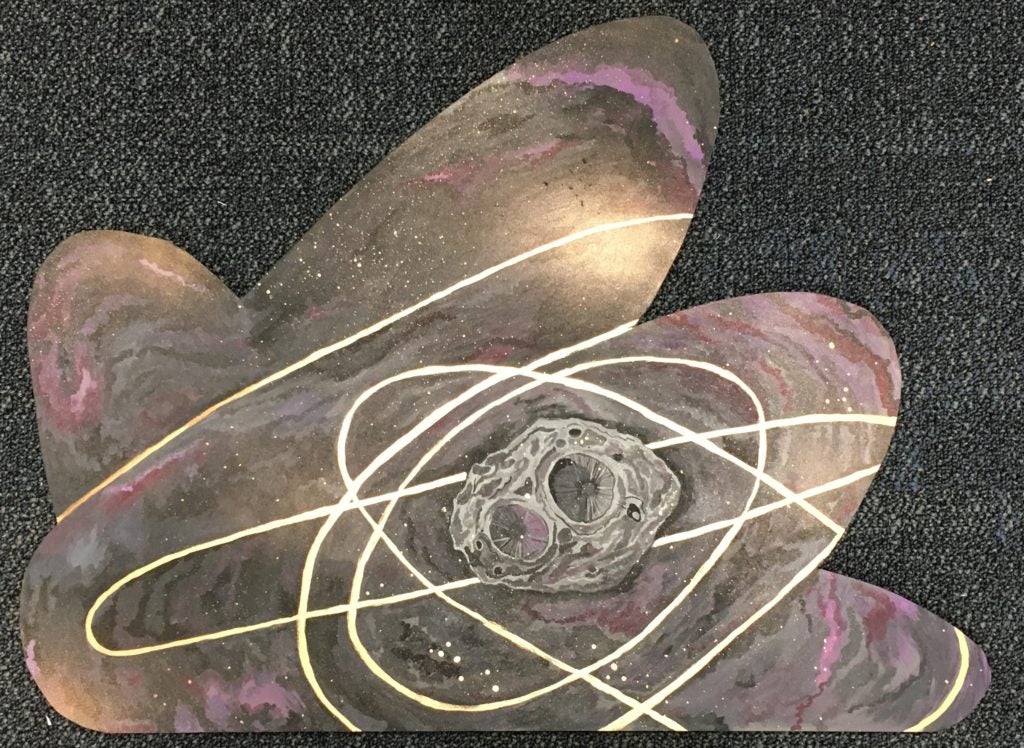 This piece shows trajectory lines framing Psyche. The project highlights the asteroid and shows the Psyche orbiter dancing with the space object. Black, purple and pink clouds were painted with rosy golds to create visual interest. Psyche is painted in the middle towards the right with rings of gold around it, signifying paths the Psyche orbiter might take. Spray paint gold was used to make speckled stars and clouds of gold in the background.