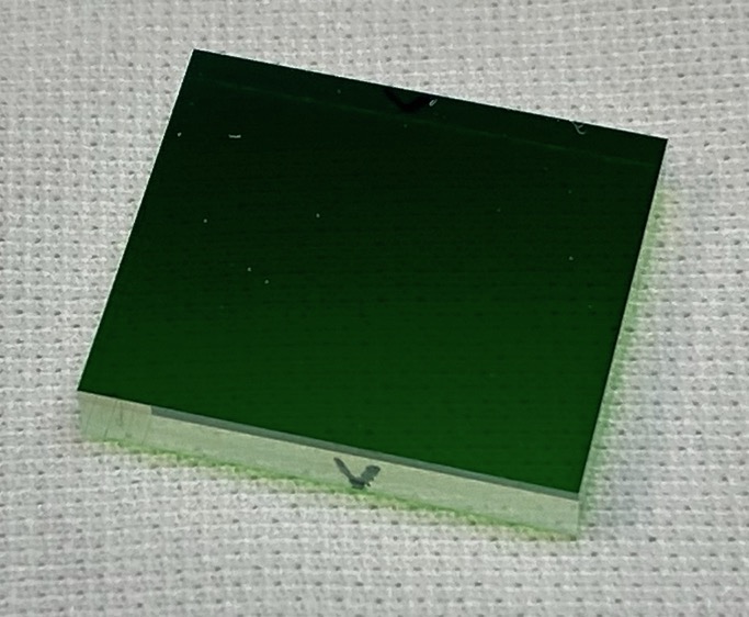 Small green glass rectangle on white woven material.