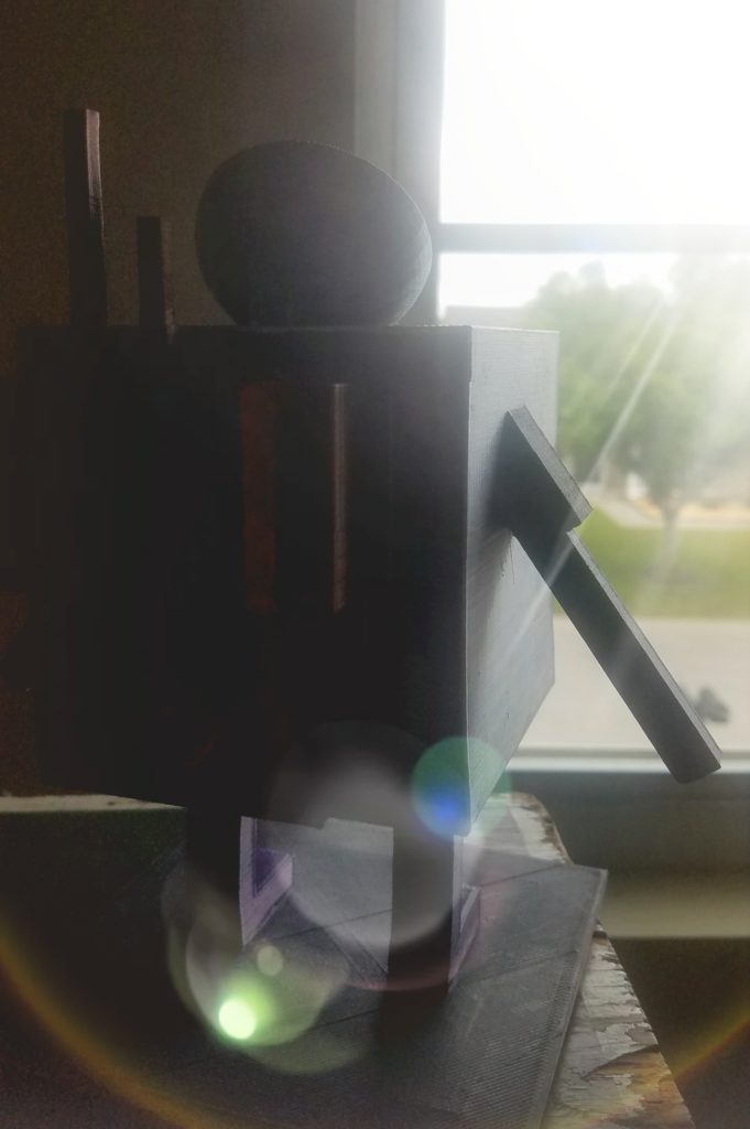 A square silver cube figure with purple rectangular arms and rectangular body stands on a table looking out a window. It has a satellite dish as a hat and wears a bronze painted cube backpack. There is a lens flare casting light into the room onto the figure's face as it looks at a tree in the distance.