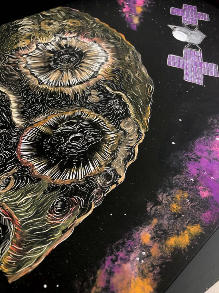 A 9 x 12 scratchboard embed with the drawing of Psyche and its satellite. To highlight the metallic texture and the colors of the Psyche mission, Psyche is contoured in a diluted gouache paint, and a more opaque form of the gouache paint in the mission's colors depict the satellite and the galaxy clouds.