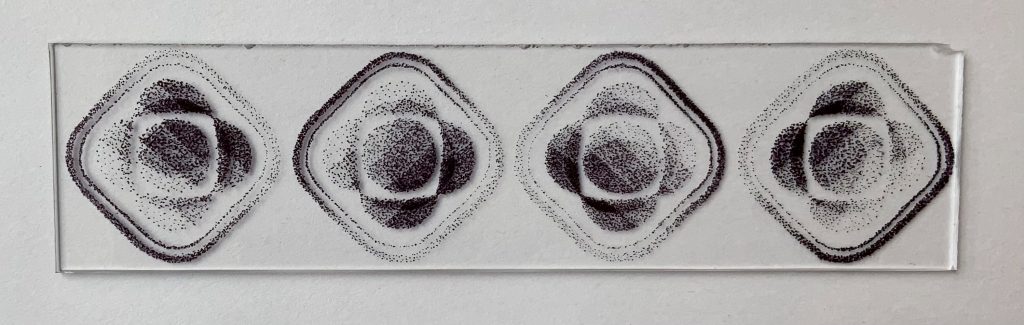 This piece consists of four parts, each made of plexiglass with black ink. Dimensions are 8 inches by 10 inches, 8 inches by 10 inches, 8 inches by 2 inches, 4 inches by 10 inches. Pointillism builds the form of the Psyche logo, the spacecraft, the orbits of the spacecraft around the asteroid, and an imagining of a crater on Psyche’s surface.
