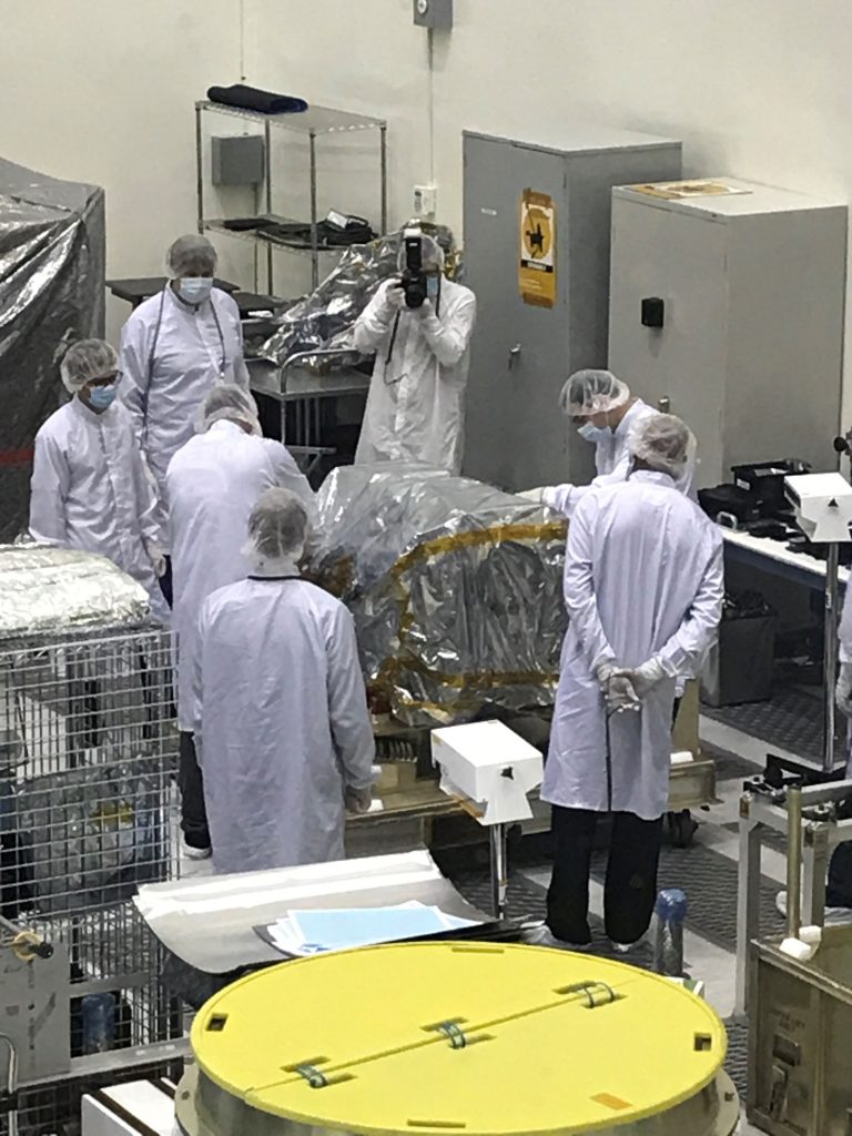 Engineers in a large room surrounded by technical equipment