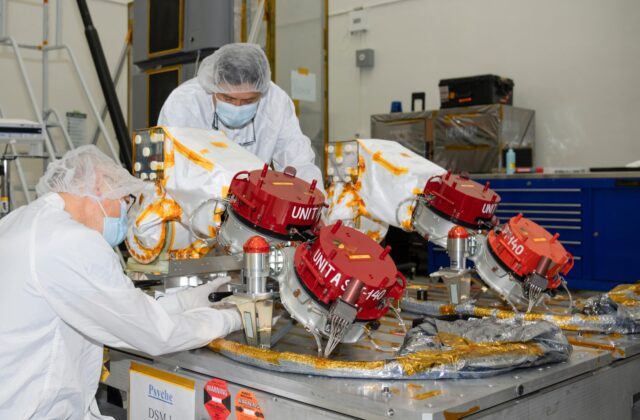 Engineers at NASA's Jet Propulsion Laboratory in Southern California prepare to integrate four Hall thrusters (beneath red protective covers) into the agency's Psyche spacecraft in July 2021.