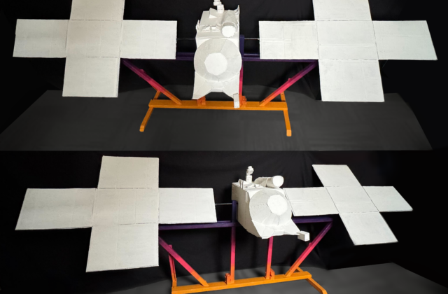 This interactive artwork recreates NASA’s Psyche spacecraft, crafted from cardboard, wood, and hot glue. The base displays Psyche's vibrant brand colors—from dark purple to mustard—while the white spacecraft invites mission team members to leave their handprints, symbolizing the unity and dedication of those who brought the Psyche mission to life.