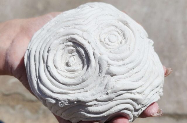 Psyche's Touch is a small plaster asteroid fits in your hand. Raised ripples radiate out like waves in water from the hand print underneath. This sculpture captures a moment of touch echoing outward, like a quiet ripple through space.